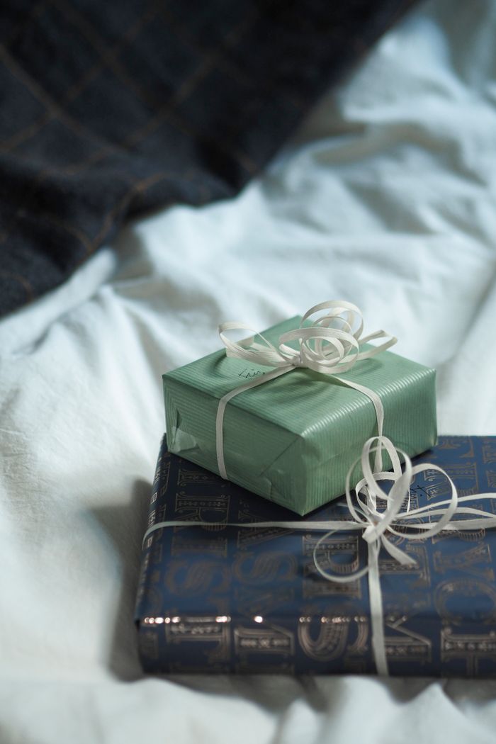 about-us-02 Two beautifully wrapped gift boxes resting on a cozy bedspread, perfect for any occasion.