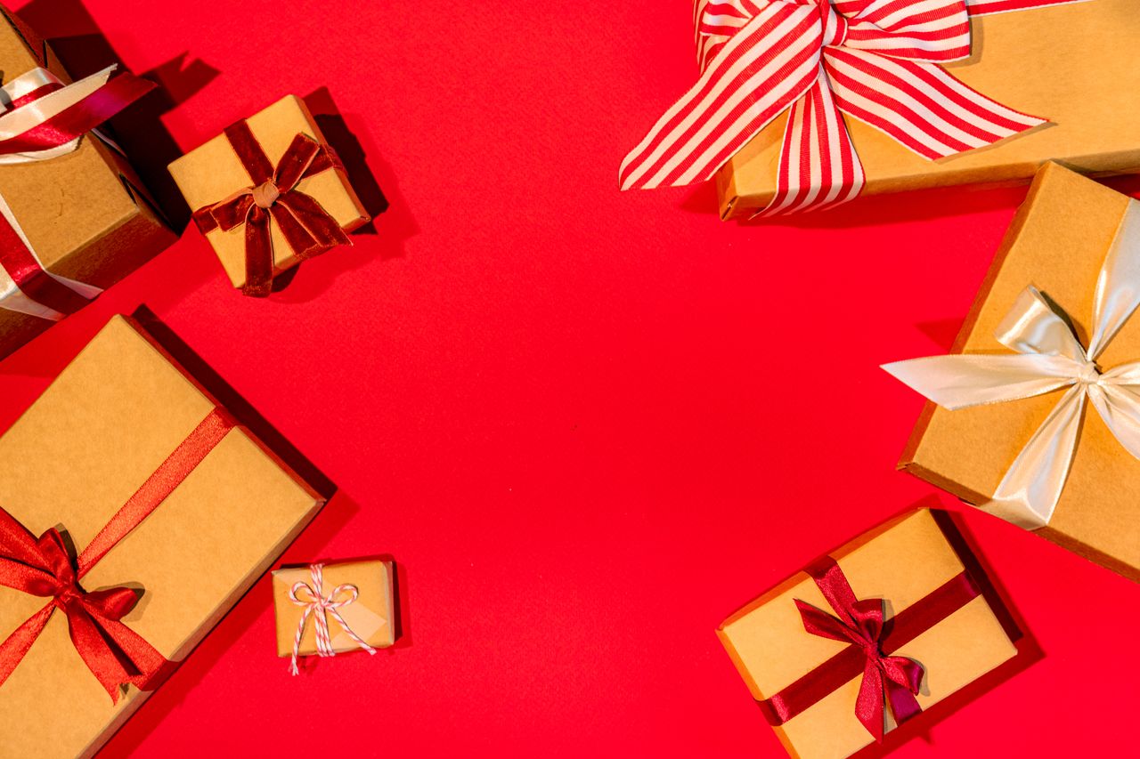hero-img A vibrant flat lay of gift boxes with ribbons on a red surface, perfect for holiday themes.