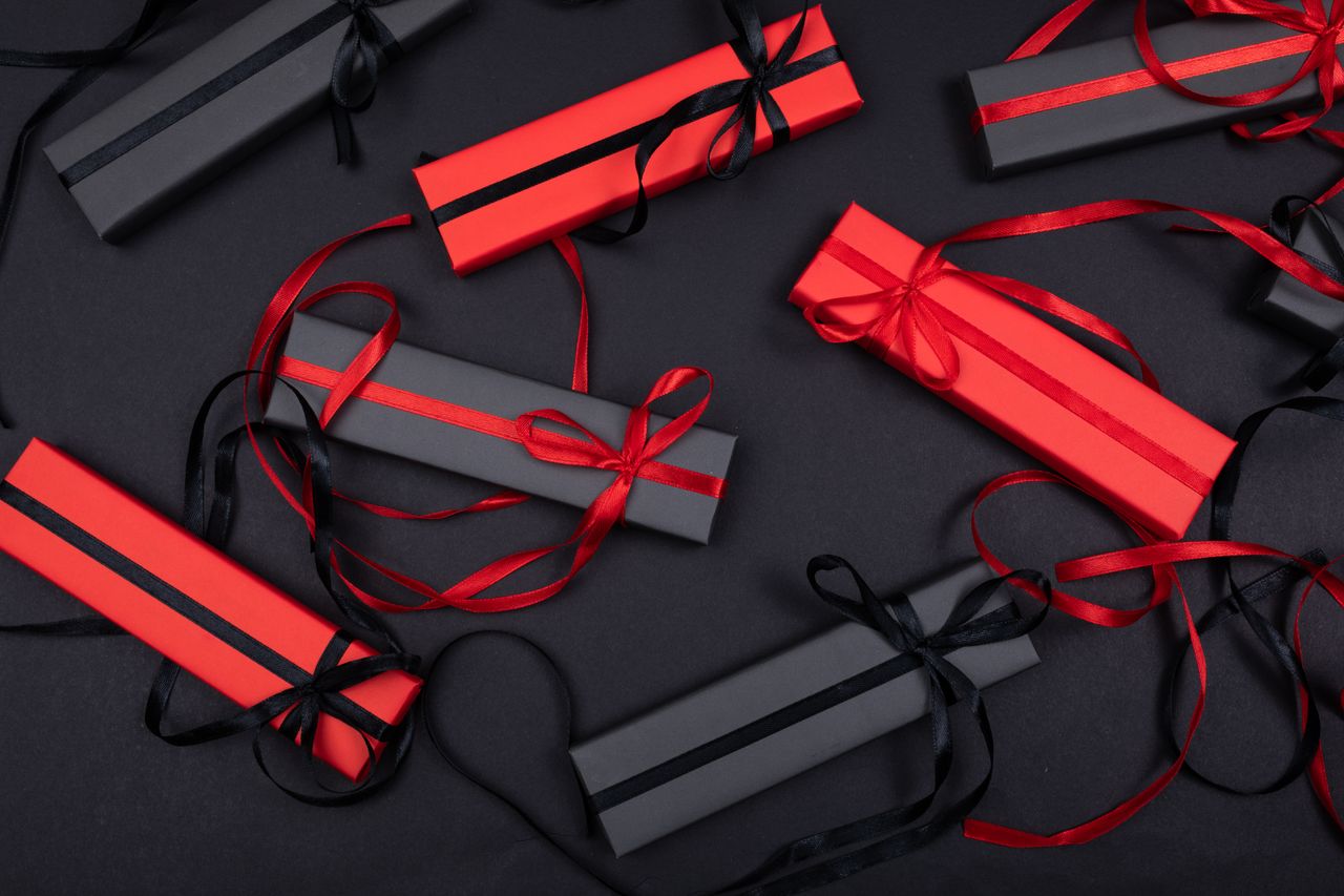 The Art of Drawing Readers In: Your attractive post title goes here Stylish flatlay of red and black gift boxes on a black surface with decorative ribbons.